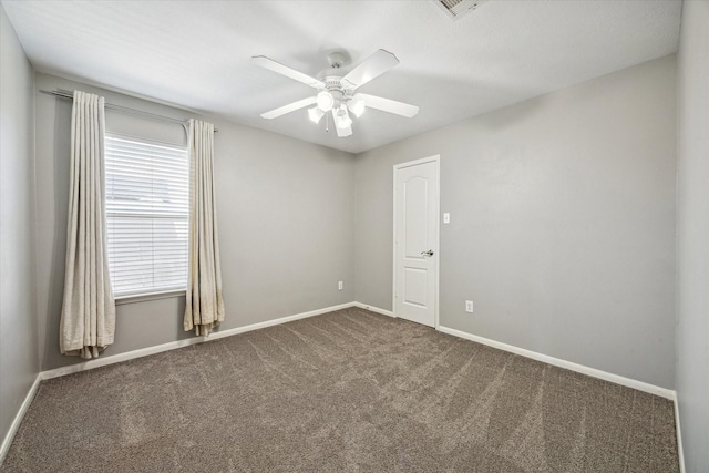 empty room with visible vents, baseboards, ceiling fan, and dark carpet