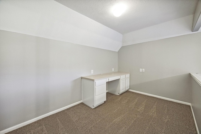 unfurnished office with baseboards, lofted ceiling, a textured ceiling, and dark carpet