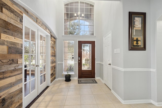 entrance foyer with tile patterned floors, french doors, baseboards, and a towering ceiling