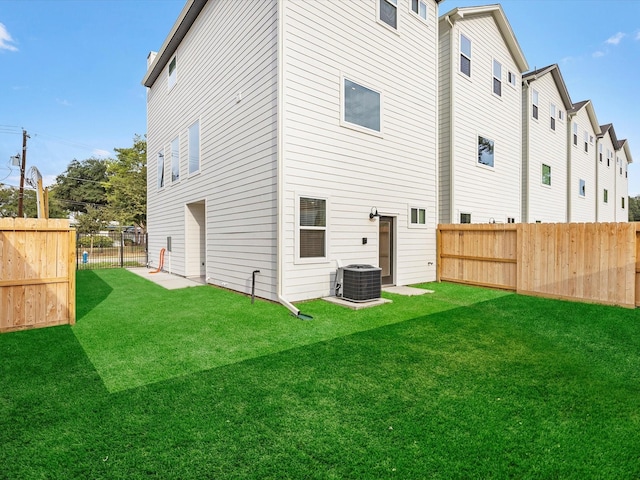 rear view of property with cooling unit, a lawn, and a fenced backyard