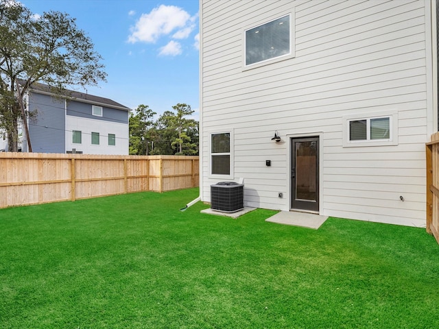 back of property featuring a lawn, central AC, and a fenced backyard