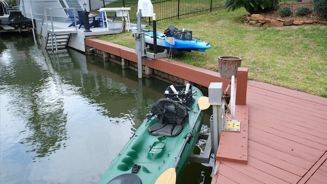 view of dock with a yard, fence, and a water view