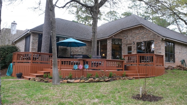 back of house featuring brick siding, a deck, and a yard