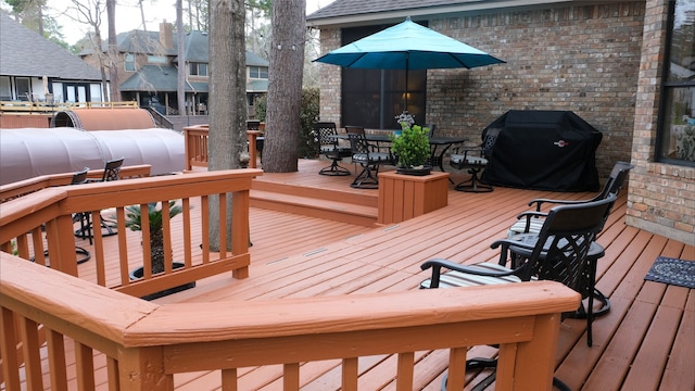 wooden terrace featuring grilling area and outdoor dining space