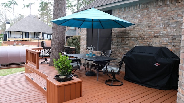 wooden terrace featuring grilling area, outdoor dining area, and heating fuel