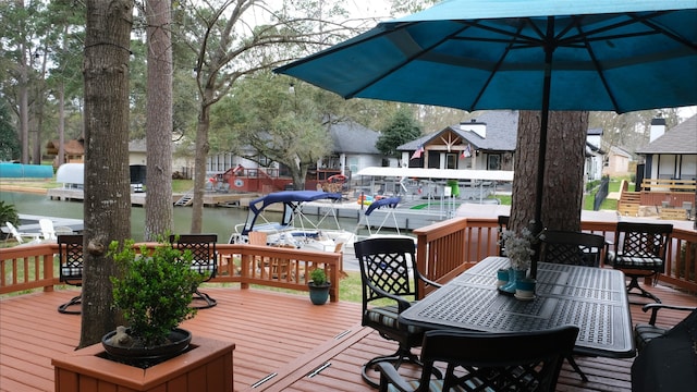 wooden deck featuring outdoor dining space, a boat dock, and a water view