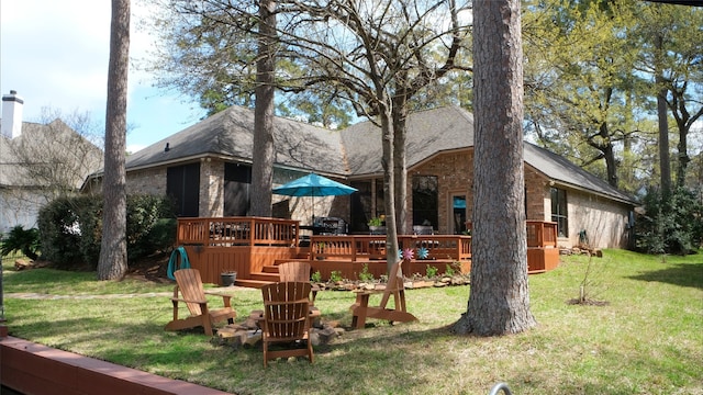 back of house featuring brick siding, a lawn, a wooden deck, and a garage