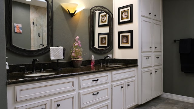 full bathroom with a sink, baseboards, a stall shower, and double vanity