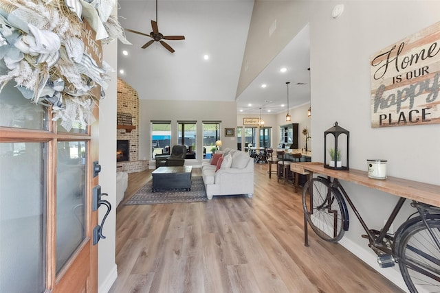 living area featuring light wood-type flooring, recessed lighting, a fireplace, high vaulted ceiling, and a ceiling fan