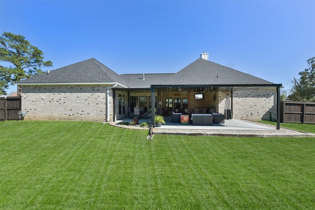 rear view of house featuring a patio area, a lawn, brick siding, and a fenced backyard