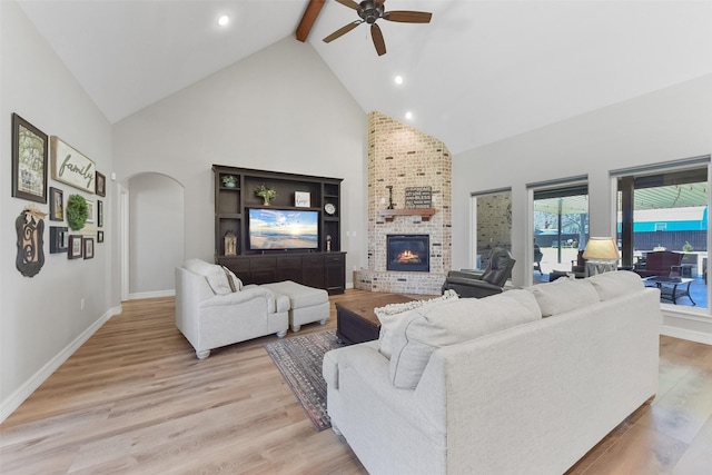 living area with baseboards, light wood finished floors, high vaulted ceiling, arched walkways, and beamed ceiling