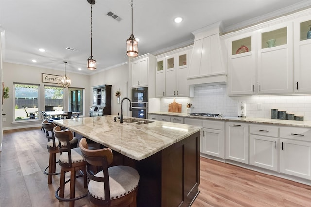 kitchen with ornamental molding, premium range hood, backsplash, and a sink