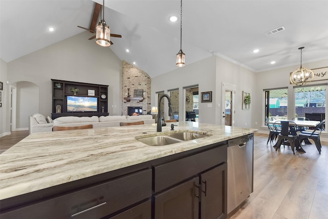 kitchen with visible vents, a sink, stainless steel dishwasher, open floor plan, and arched walkways