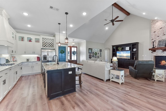 kitchen with light wood finished floors, visible vents, open floor plan, and stainless steel refrigerator with ice dispenser