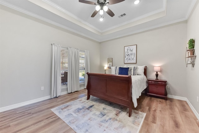 bedroom with visible vents, crown molding, baseboards, a tray ceiling, and wood finished floors