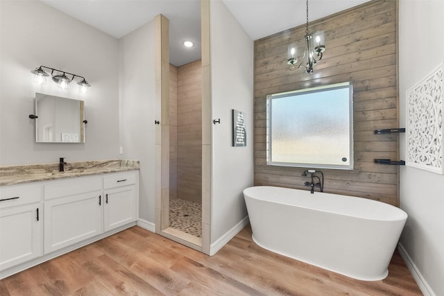 bathroom featuring baseboards, tiled shower, wood finished floors, a soaking tub, and vanity