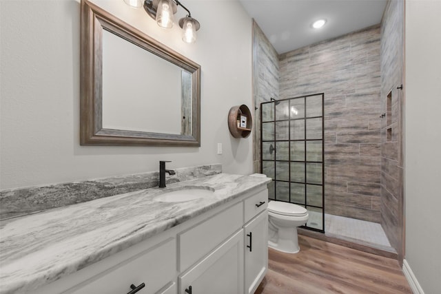 full bathroom with toilet, walk in shower, wood finished floors, and vanity