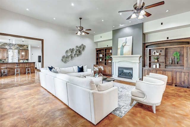 living area with recessed lighting, a glass covered fireplace, a ceiling fan, and light tile patterned floors