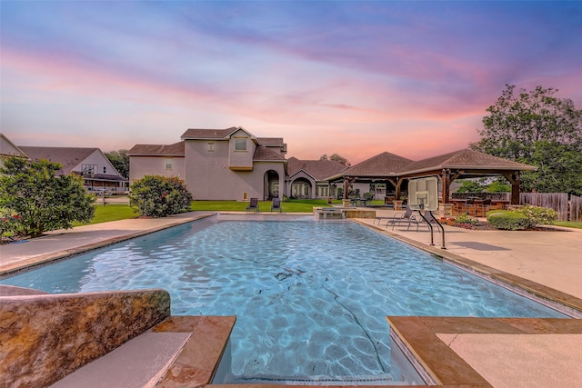 pool at dusk featuring a gazebo, a fenced in pool, fence, and a patio