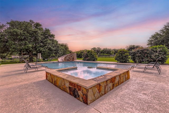 view of pool featuring a patio area, a water slide, an in ground hot tub, and fence