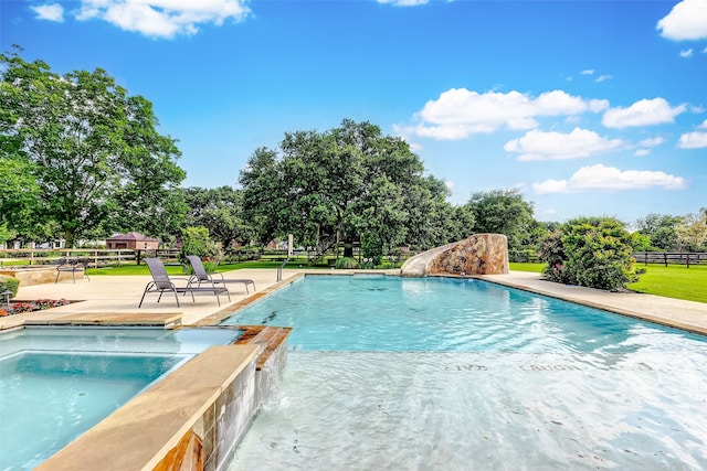 view of swimming pool featuring a patio area, a pool with connected hot tub, a water slide, and fence