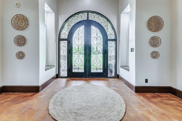 foyer with tile patterned floors, french doors, and baseboards