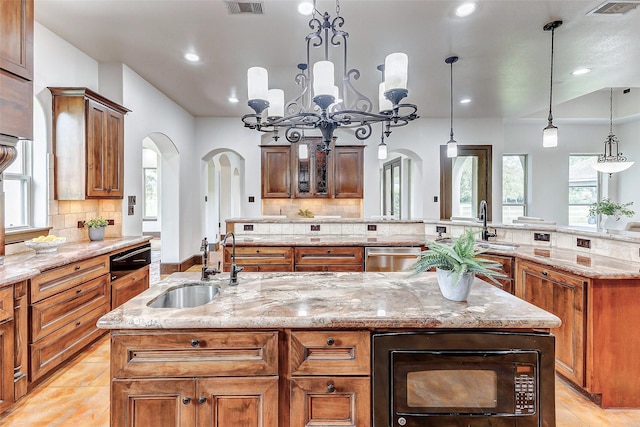 kitchen featuring a large island, a sink, stainless steel dishwasher, arched walkways, and black microwave