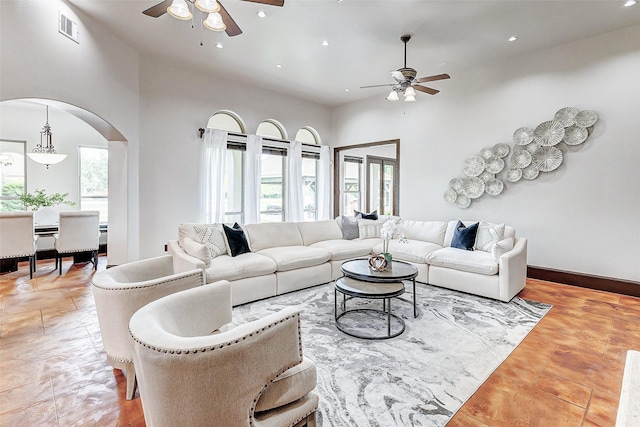 living room with arched walkways, visible vents, a wealth of natural light, and ceiling fan