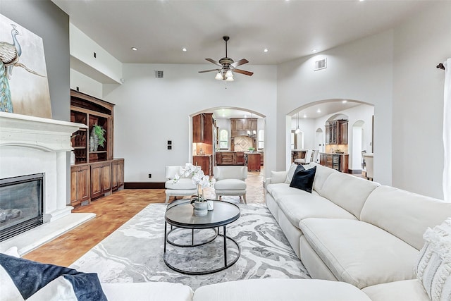 living room with a ceiling fan, visible vents, a premium fireplace, recessed lighting, and arched walkways