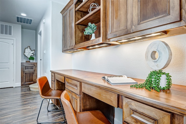 office space featuring visible vents, dark wood-style flooring, and built in study area