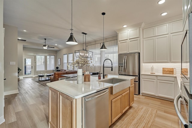 kitchen with tasteful backsplash, stainless steel appliances, light wood-style floors, and a sink