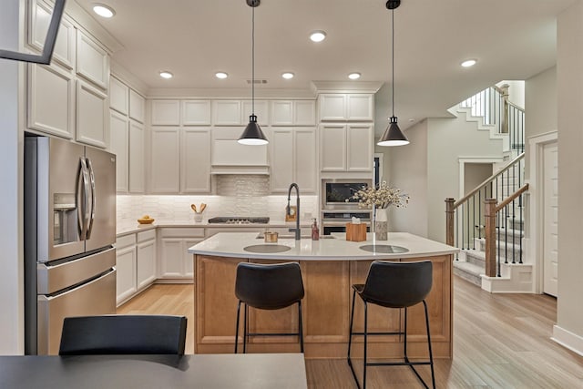 kitchen with light countertops, white cabinets, appliances with stainless steel finishes, and a sink