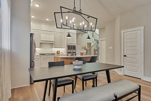 dining room with light wood finished floors, baseboards, stairway, recessed lighting, and an inviting chandelier