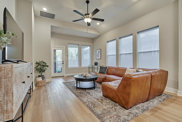 living room with visible vents, baseboards, light wood-style floors, and vaulted ceiling