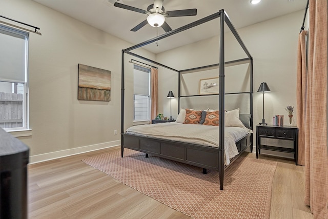 bedroom with multiple windows, baseboards, wood finished floors, and a ceiling fan