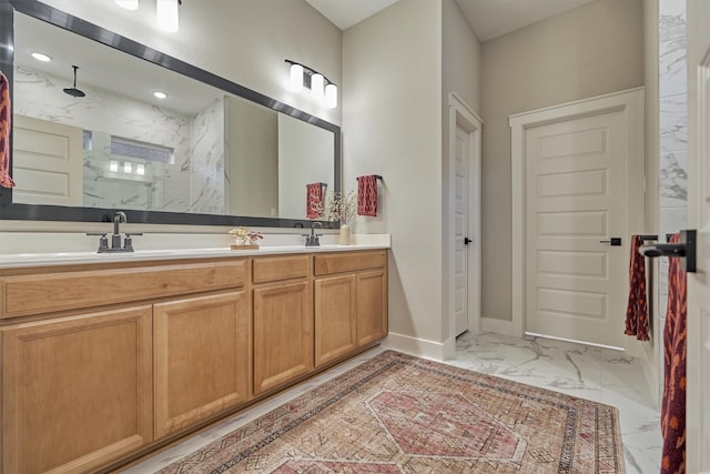 full bathroom with marble finish floor, a sink, a marble finish shower, double vanity, and baseboards