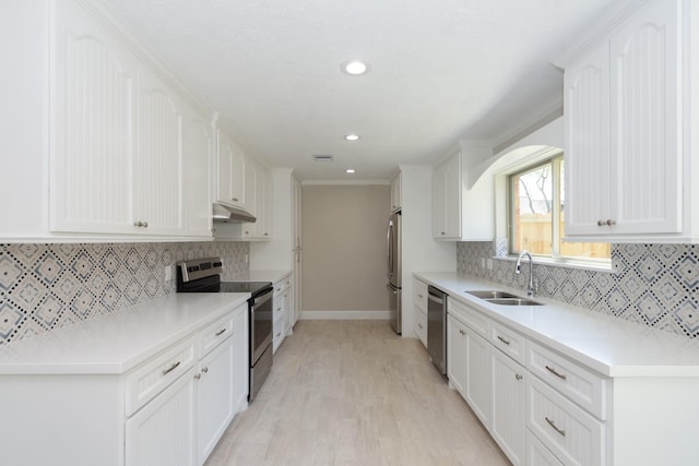 kitchen featuring light wood-style flooring, a sink, under cabinet range hood, stainless steel appliances, and white cabinets