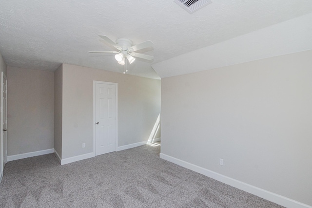 unfurnished room with visible vents, carpet flooring, a textured ceiling, and baseboards