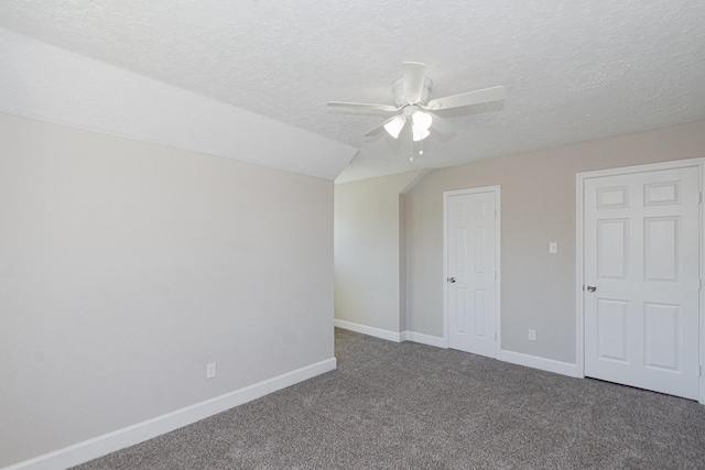 unfurnished bedroom featuring a textured ceiling, lofted ceiling, baseboards, and carpet floors