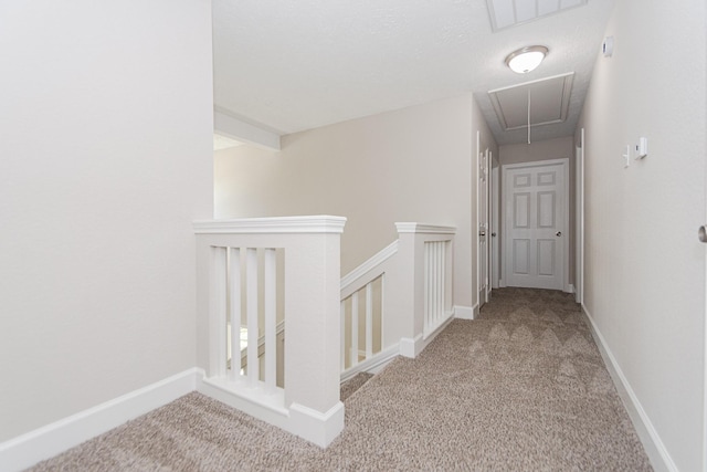 hall with baseboards, an upstairs landing, carpet, and attic access