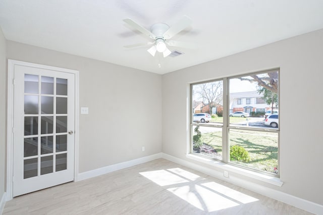 empty room with visible vents, a ceiling fan, baseboards, and wood finished floors