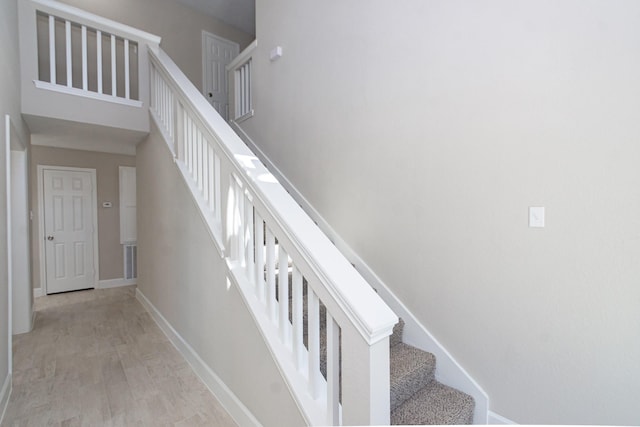 staircase featuring a high ceiling, wood finished floors, and baseboards