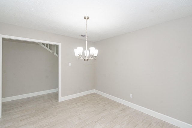 empty room featuring visible vents, baseboards, a notable chandelier, and light wood-style flooring