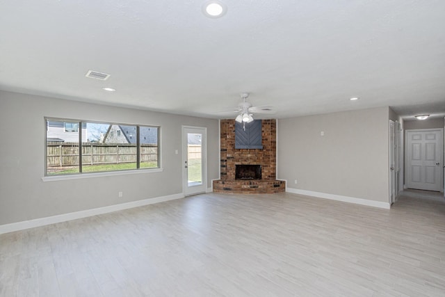 unfurnished living room with visible vents, a ceiling fan, a fireplace, and light wood finished floors