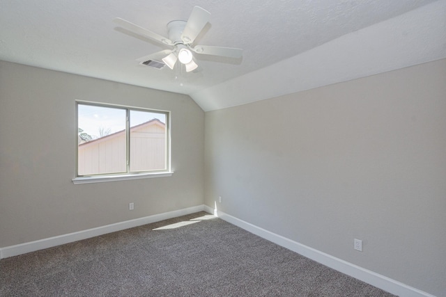 carpeted spare room featuring lofted ceiling, baseboards, visible vents, and ceiling fan