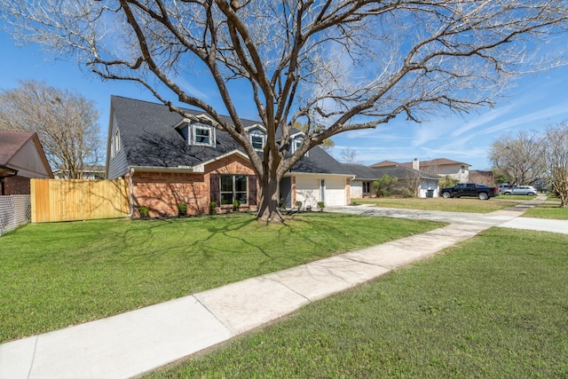 view of front facade with brick siding, fence, concrete driveway, a front yard, and an attached garage