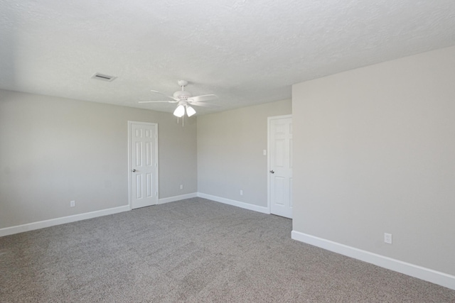 carpeted spare room featuring visible vents, baseboards, a textured ceiling, and ceiling fan