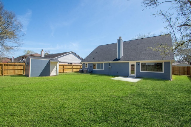 back of property featuring a yard, an outdoor structure, a storage shed, and a fenced backyard