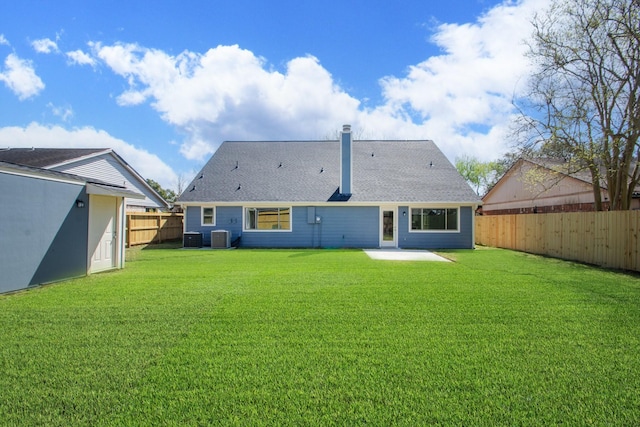 rear view of property featuring central air condition unit, a patio, a lawn, and a fenced backyard