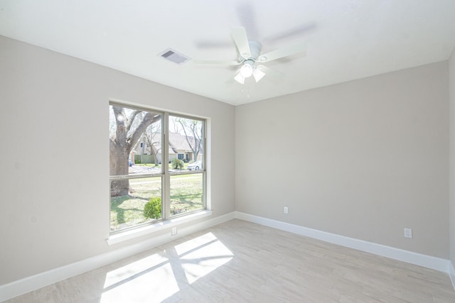 empty room featuring a ceiling fan, light wood-style flooring, baseboards, and visible vents